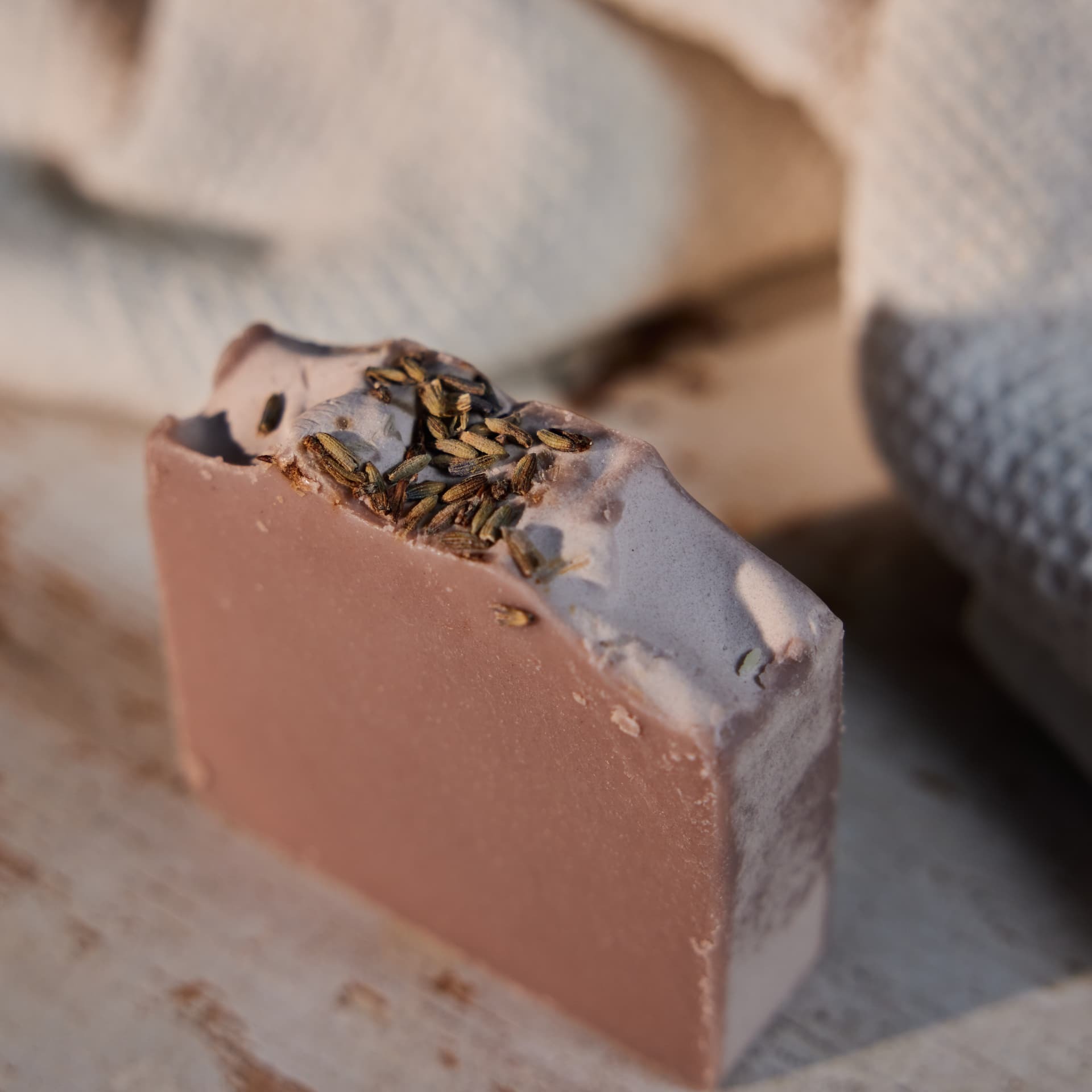 Close detail of a rose clay soap bar topped with dried lavender buds